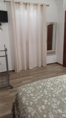 a bedroom with white curtains and a bed and a mirror at A Lapa in Mourão