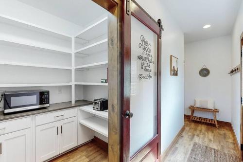 a kitchen with white cabinets and a microwave and a door at Some Kind of Wonderful-Escape Near Seneca Lake in Senecaville