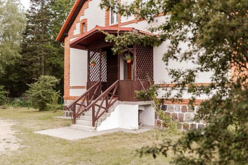 a house with a porch and a wooden staircase at Leśniczówka Gołębia Góra in Unichowo