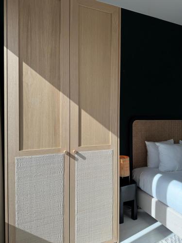 a wooden cabinet with two doors next to a bed at 3 Room Luxury Design Apartment with Airconditioning, Close to Gent St-Pieters Station in Ghent