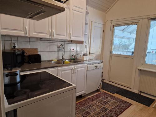 a kitchen with white cabinets and a sink at Mysig Stuga Och Hotell I Karlskrona in Karlskrona