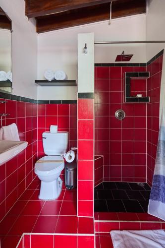 a red tiled bathroom with a toilet and a sink at Perla de la Playa Beachfront Hotel in Tamarindo