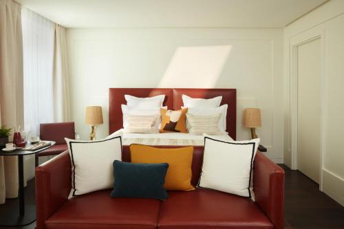 a bedroom with a bed with a red couch with pillows at Hotel La Villa Saint Germain Des Prés in Paris