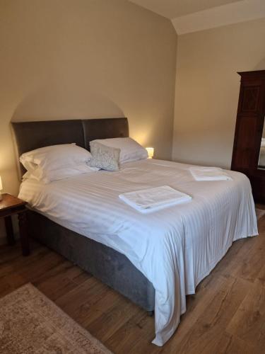 a bedroom with a large bed with white sheets and pillows at Broomhill Barns in Minwear