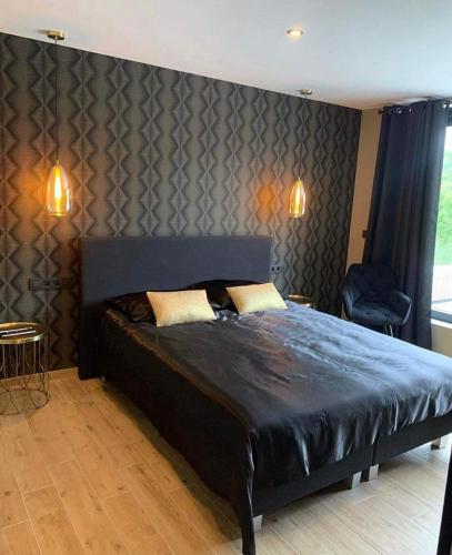 a bedroom with a large bed with a black headboard at La villa M in Sart-lez-Spa