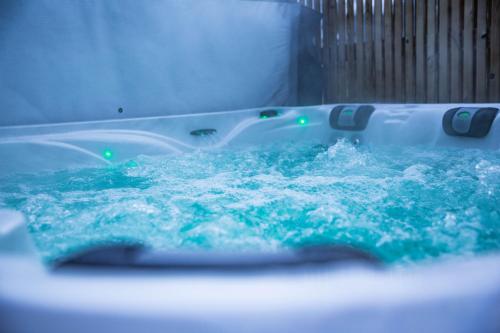a bath tub filled with blue water with bubbles at La villa M in Sart-lez-Spa