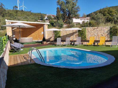 einen Pool im Garten mit Stühlen und Sonnenschirmen in der Unterkunft Da Serra guesthouse in Porto de Mós