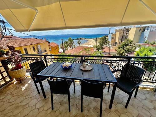 a table on a balcony with chairs and an umbrella at Bratis House Arkoudi in Arkoudi