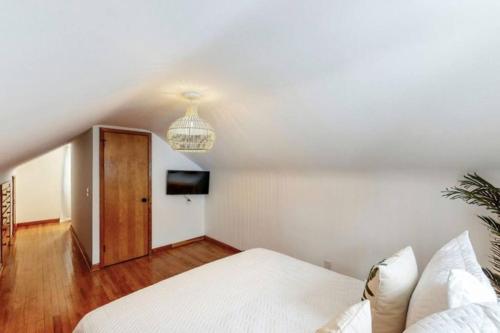 a white bedroom with a bed and a chandelier at The Playmakers Funhouse-HOF Village in Canton