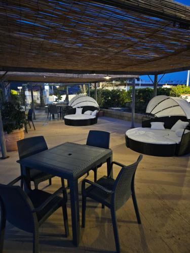 eine Terrasse mit einem Tisch, Stühlen und einem Bett in der Unterkunft Graceland rooms and suites in Capo Vaticano