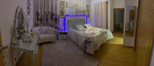 a bedroom with a bed and a chair and purple lights at NuriahBoutique Sacavém in Sacavém