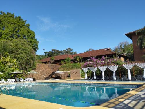 einen Pool mit Stühlen und Sonnenschirmen neben einem Gebäude in der Unterkunft Hotel Raices Esturion in Puerto Iguazú