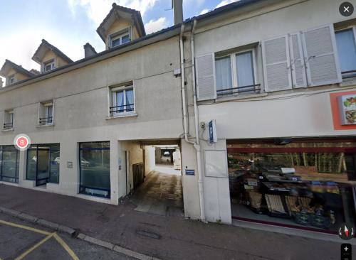 un bâtiment blanc avec une porte ouverte sur une rue dans l'établissement Coin Cosy à Verneuil, à Verneuil-sur-Seine