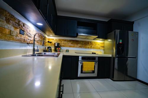 a kitchen with black cabinets and a sink and a refrigerator at Apartamentos La Casona in Fortuna