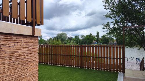 a wooden fence with green grass next to a body of water at Dunaparti vendégház in Ráckeve