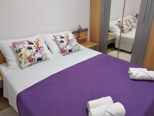斯塔利格拉德－帕克萊尼采的住宿－Apartment Savic，一间卧室配有一张大床,提供紫色床单和枕头