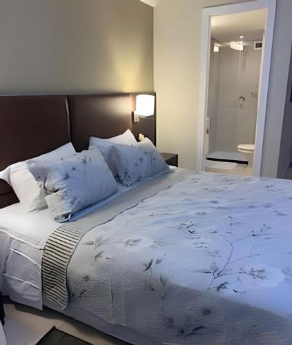 a bedroom with a large bed with white sheets and pillows at Studio pé na areia, vista, internet e ar in Macaé