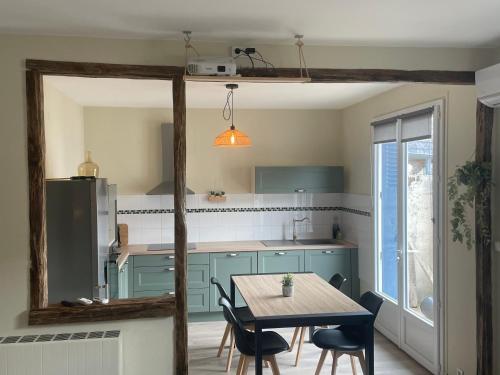 une cuisine avec des placards bleus et une table avec des chaises dans l'établissement Le Rupin, à Brive-la-Gaillarde