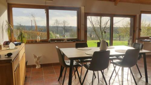 une salle à manger avec une table, des chaises et des fenêtres dans l'établissement REVES DE BAIE - Accueillant, Paisible, Vue panoramique exceptionnelle, à Tirepied