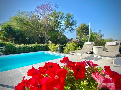 una piscina con due sedie e fiori rossi di Yurta Arco Iris a Riba-Roja De Túria