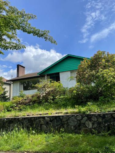 a house with a green roof and a stone wall at Green House in Vancouver West in Vancouver