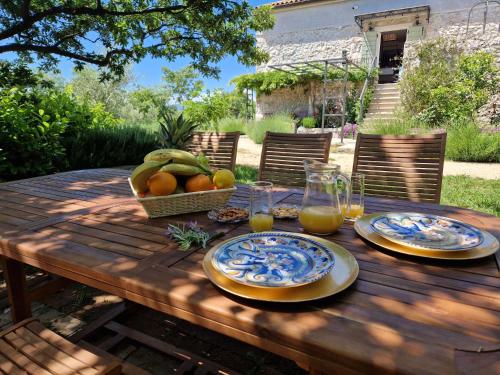 a wooden table with plates of fruit and glasses of orange juice at Stone House Rosuja in Ivanje