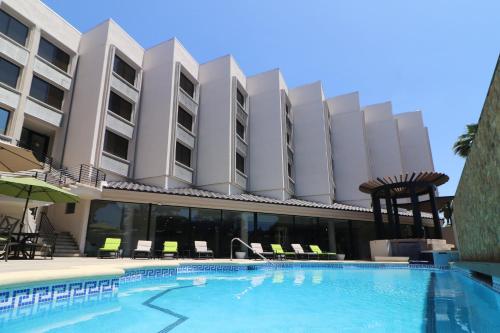 a hotel with a swimming pool in front of a building at Holiday Inn Tijuana Zona Rio by IHG in Tijuana