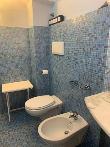 a blue tiled bathroom with a toilet and a sink at Villa CieloMare in Camogli
