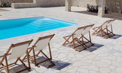 a group of chairs sitting next to a swimming pool at Villa celine in Aliki