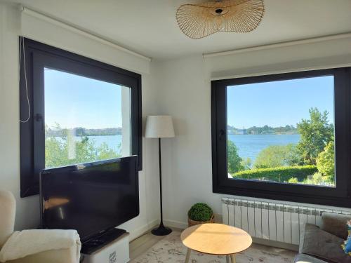 a living room with two large windows and a flat screen tv at La Casita de la bahía in Pontejos