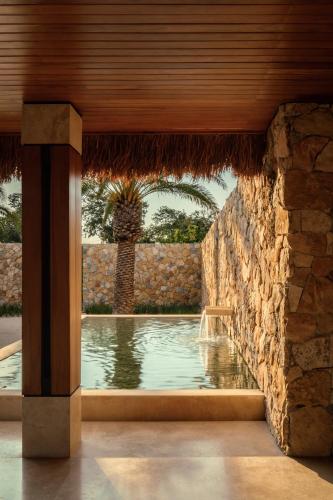 a swimming pool in a house with a stone wall at Residencia Hacienda Chablé in Chocholá