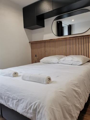 - un lit avec 2 oreillers blancs et un miroir dans l'établissement T2 pour 4, proche Versailles, Paris et La Défense, à Le Port-Marly