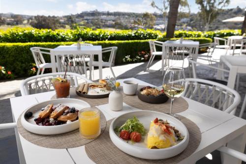 Omni La Costa Resort & Spa Carlsbad في كارلسباد: طاولة مع أطباق من الطعام وكؤوس من النبيذ
