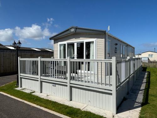 ein kleines Haus mit einem weißen Zaun in der Unterkunft The Retreat 16 - pet friendly, WiFi, and a bath - Golden Palm Resort - Meadow Lakes Caravan & Lodge Hire in Chapel Saint Leonards