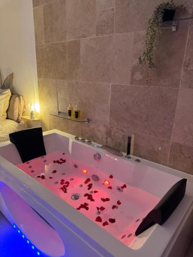 une baignoire remplie de pétales rouges dans une pièce dans l'établissement l'Idylle - Coeur de Bastide - balnéo - Clim, à Carcassonne