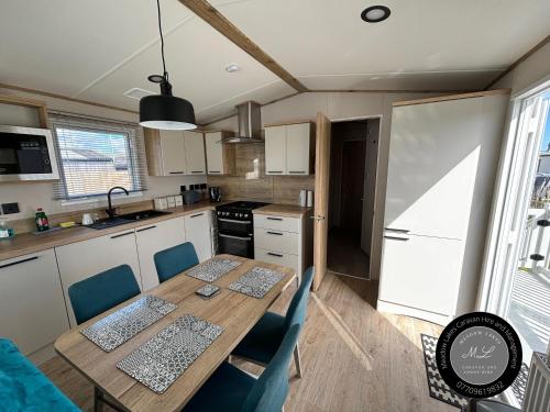 eine Küche mit einem Holztisch und Stühlen in der Unterkunft The Retreat 16 - pet friendly, WiFi, and a bath - Golden Palm Resort - Meadow Lakes Caravan & Lodge Hire in Chapel Saint Leonards