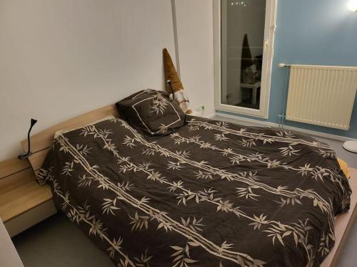 un lit avec une couverture marron et un sac dessus dans l'établissement Le clos des lilas - Vitry sur Seine, à Vitry-sur-Seine