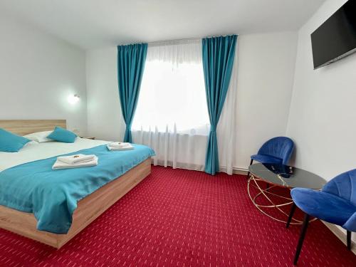 a bedroom with a bed and blue chairs and a window at Milea's Guesthouse in Bran