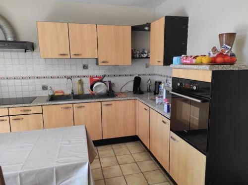 une cuisine avec des armoires en bois et un réfrigérateur noir dans l'établissement Maison entre Nice et Monaco, à Blausasc