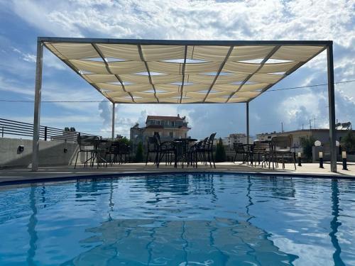 a canopy over a swimming pool with tables and chairs at Vullkan Hotel in Ksamil
