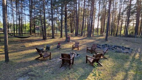 a group of wooden benches in a park with trees at Sena Troba in Druskininkai
