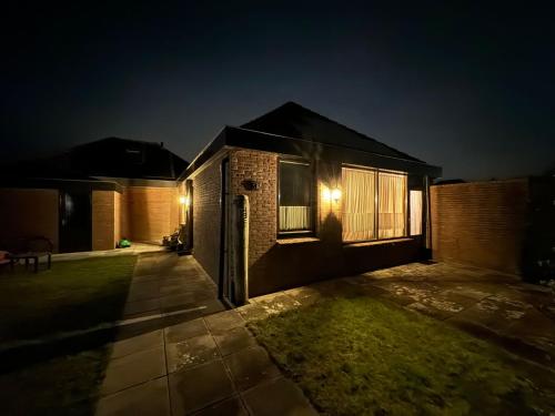 a house with lights on the side of it at night at De Zonneplek in Herkingen