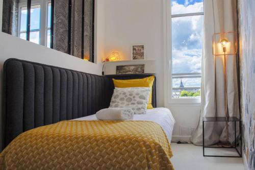 een slaapkamer met een bed met een gele deken en een raam bij SweetHomeVersailles 5mn walk from the Palace in Versailles