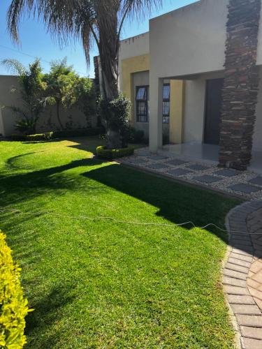 a green yard with a house and a palm tree at Maso palace in Polokwane