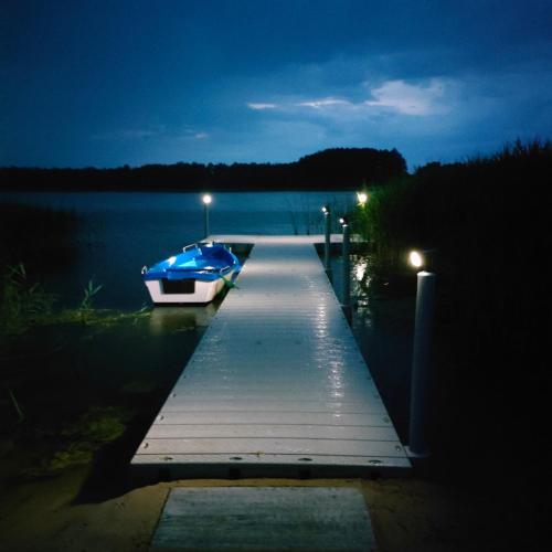 a boat parked at a dock on a lake at night at Przystań Nad Miążką in Sapowice