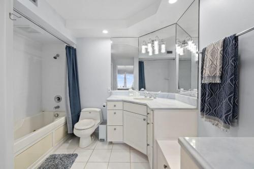 La salle de bains blanche est pourvue de toilettes, d'une baignoire et d'un lavabo. dans l'établissement Siesta Beach Retreat Poolside Paradise 2BR Condo, à Siesta Key