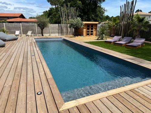 une piscine avec une terrasse en bois à côté d'une cour arrière dans l'établissement Magnifique Villa Lege Cap Ferret avec piscine, à Lège-Cap-Ferret