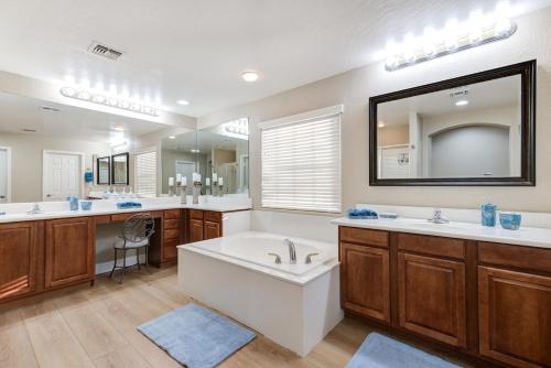 La salle de bains est pourvue d'une baignoire, de 2 lavabos et d'un miroir. dans l'établissement 5BR Lux Paradise Pool Spa Resort Backyard Bliss, à Chandler