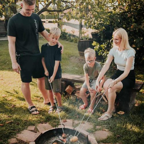 a family is standing around a fire pit at RANČ JUREŠ in Ljutomer
