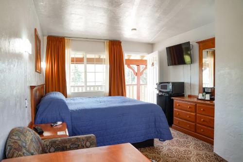a bedroom with a blue bed and a tv at Swiss Holiday Lodge in Mount Shasta